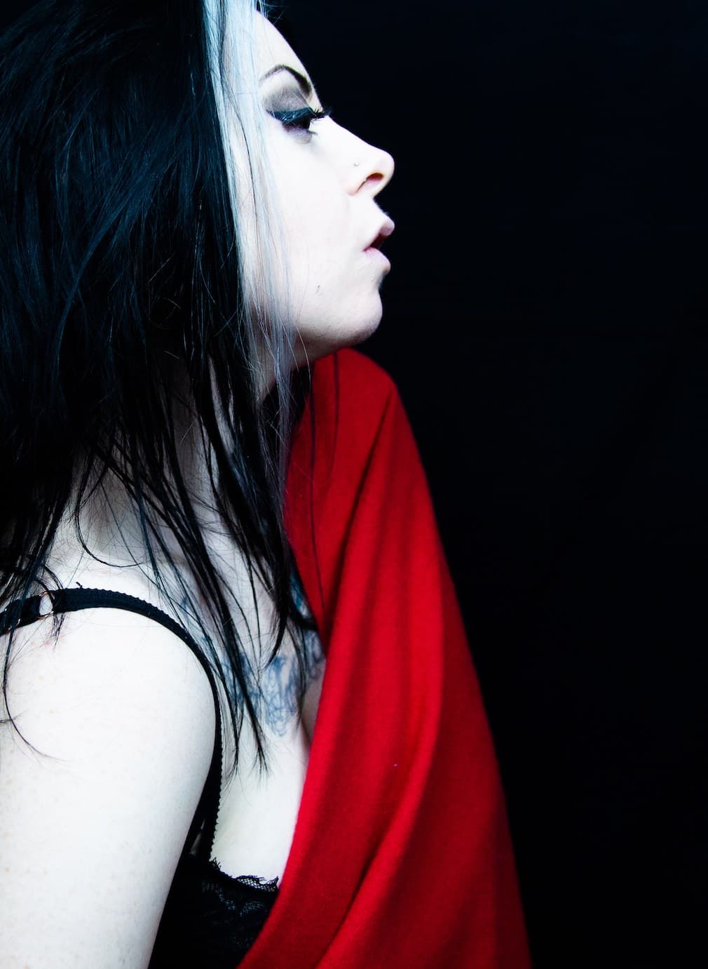 Mari Kattman in profile against black, a red cloth over her shoulder